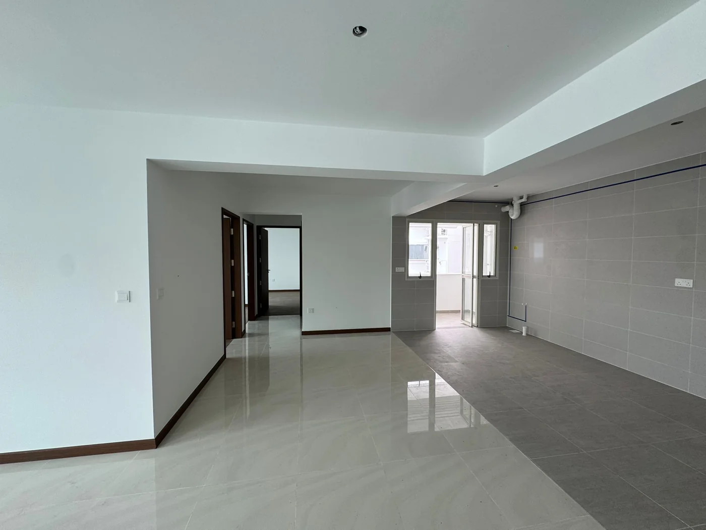 A new BTO flat before renovation: an empty living, dining and kitchen area with white walls and new floor tiles